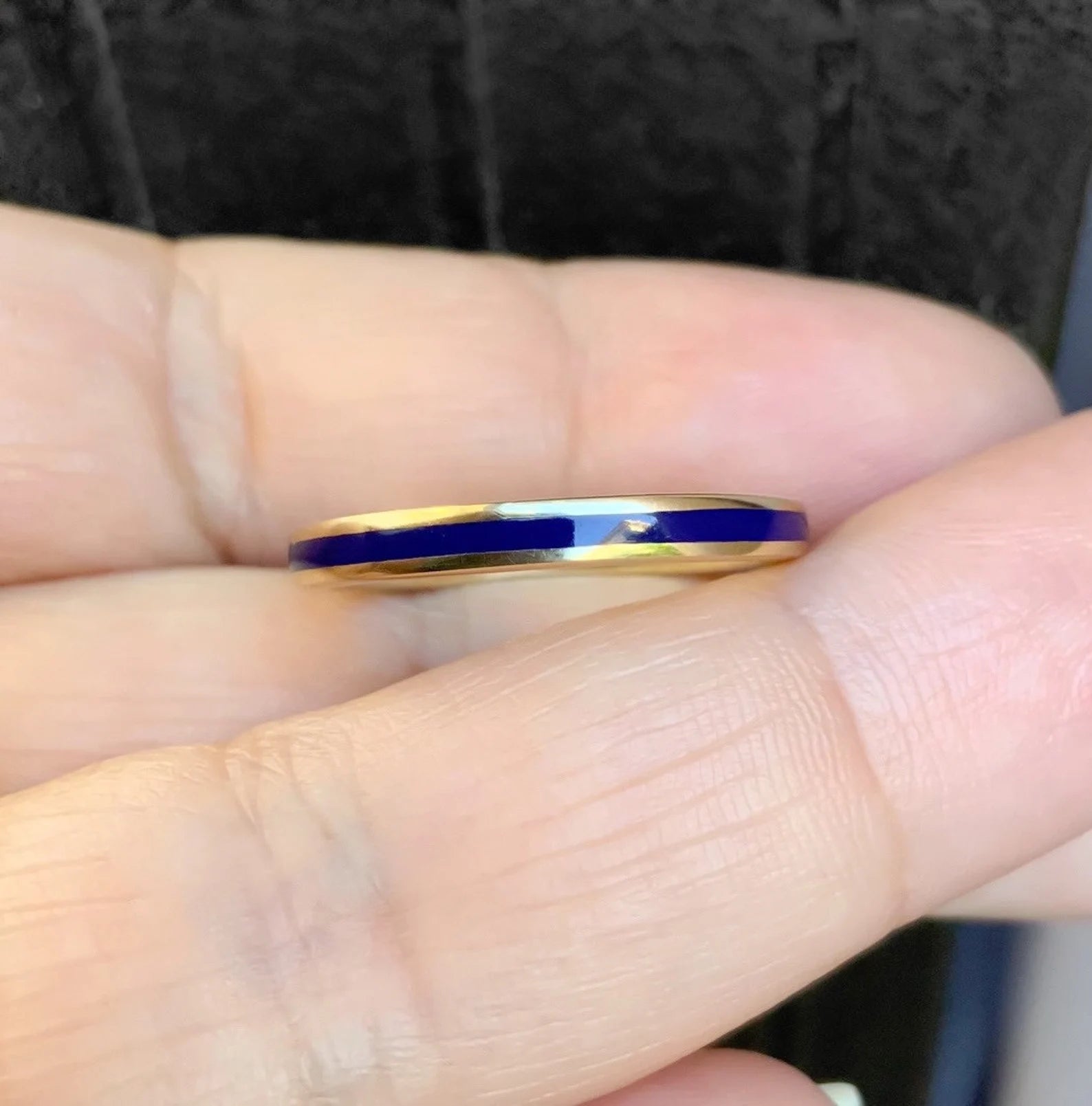 Navy blue enamel stacking ring in 14K yellow gold, held between fingers showing the continuous enamel wrap and high-polish band profile.